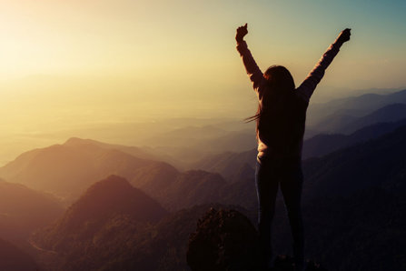 Woman arms up on top of mountain